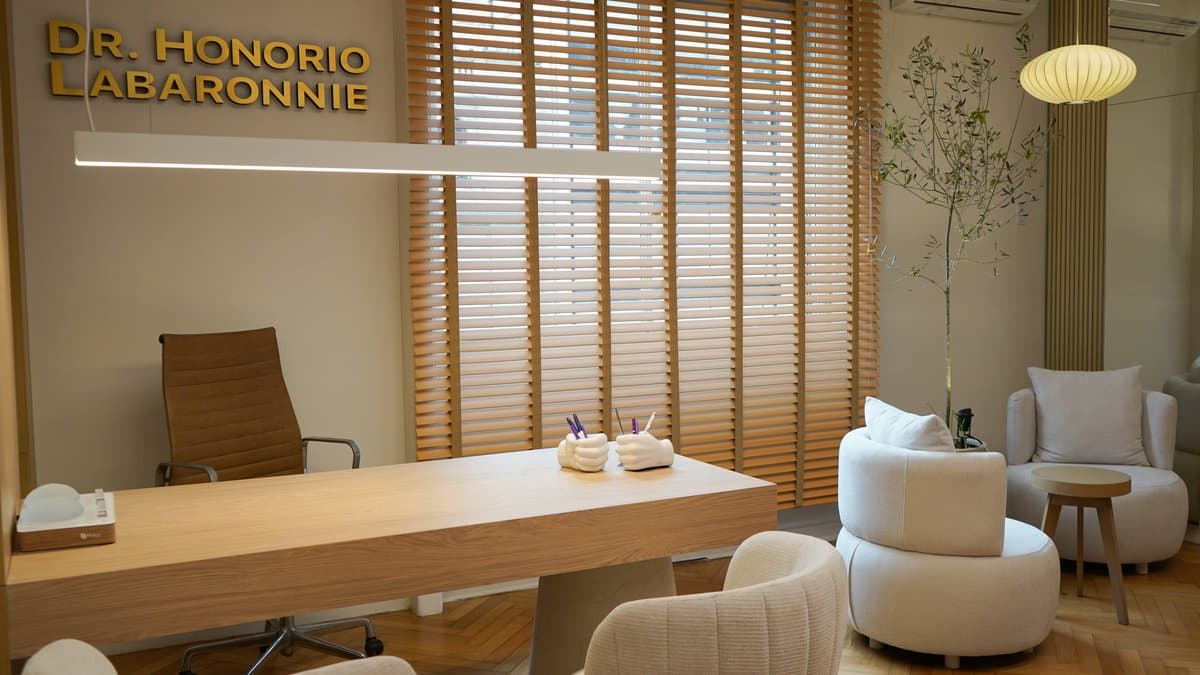 Consultorio principal del Dr. con escritorio de madera, sillas y lámpara colgante esférica