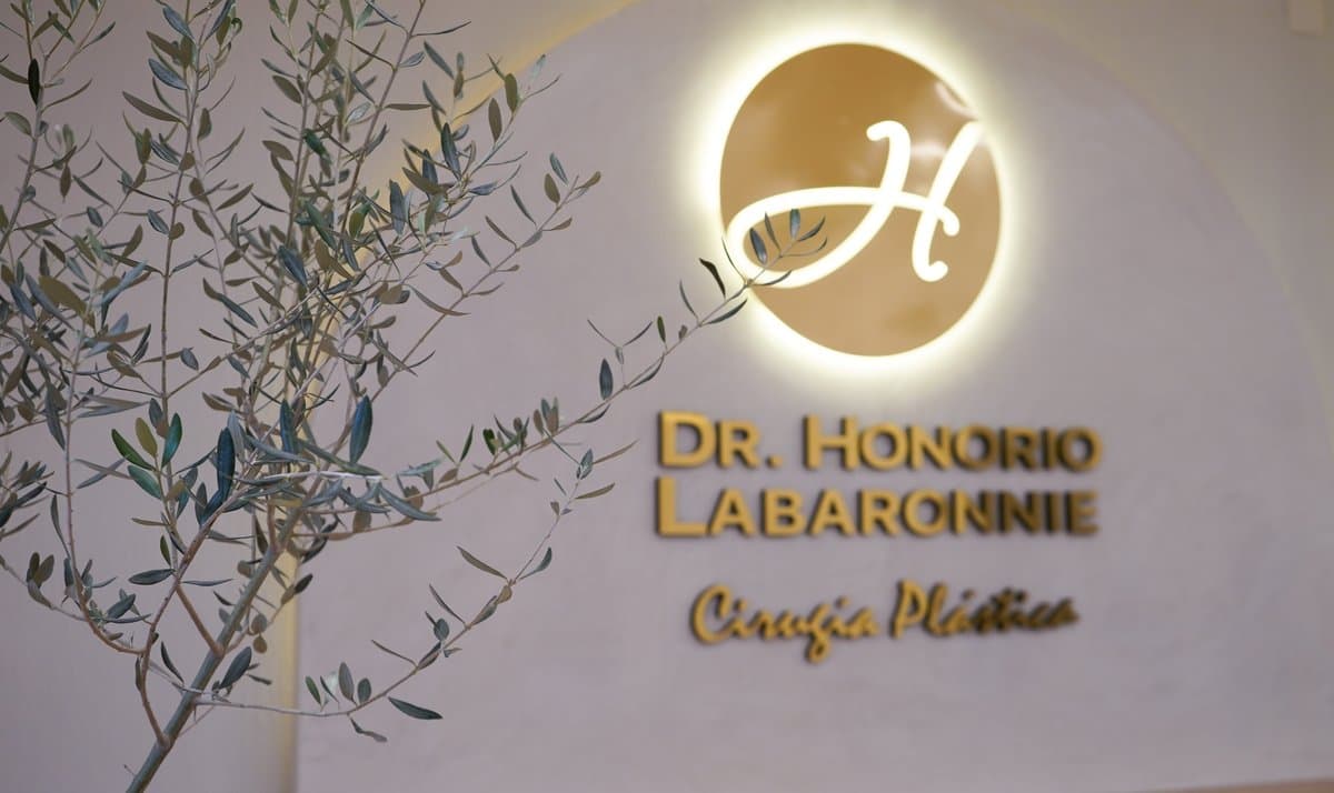 Logo Dr. Honorio Labaronnie en pared dorada iluminada con un olivo en primer plano